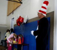Image: Arnold Neilson, playing the Cat in the Hat, greets families entering the youth center for the Dr. Seuss celebration.
