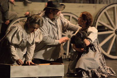 Image: Auntie Em (Sara Sidwell), Uncle Henry (Tyler Jones), Dorothy (Azure Kline), and Toto (Heist) in a serious discussion at the beginning of the play.
