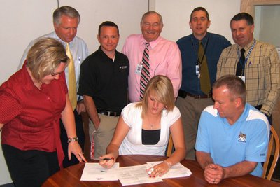 Image: Signing — Amy Andrus signing her letter of intent for Metropolitan State College of Denver with head coach Paul Anderson (front right) and (back) Jamie Andrus, mom; David Swenson, principal; Marcus Maw, athletic trainer; Jan Hall, athletic director; Tim Smith, assistant principal; and Joel Allred, assistant principal.