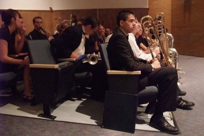 Image: Watching and waiting — Members of the Symphonic Band sit with instruments in hand while the Concert Band performs on stage.