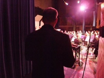 Image: Beach waits — After changing places, the Symphonic Band warms up on stage while Director Randall Beach waits off stage to make his entrance.