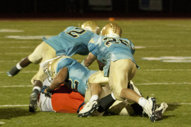 Image: Milyon Chantry (2), Tre’ Hansen (52), and Cole Bangerter (25) team up for a tackle.