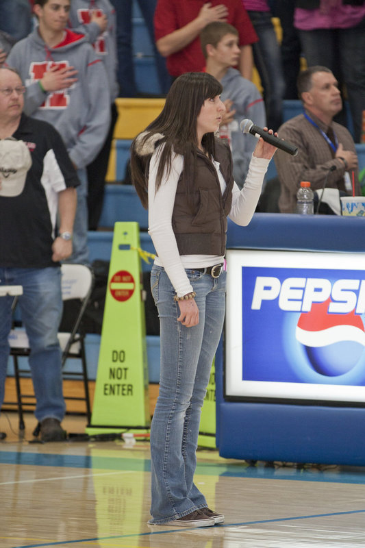 Image: Kelsey Lee sings the national anthem to get the game under way.